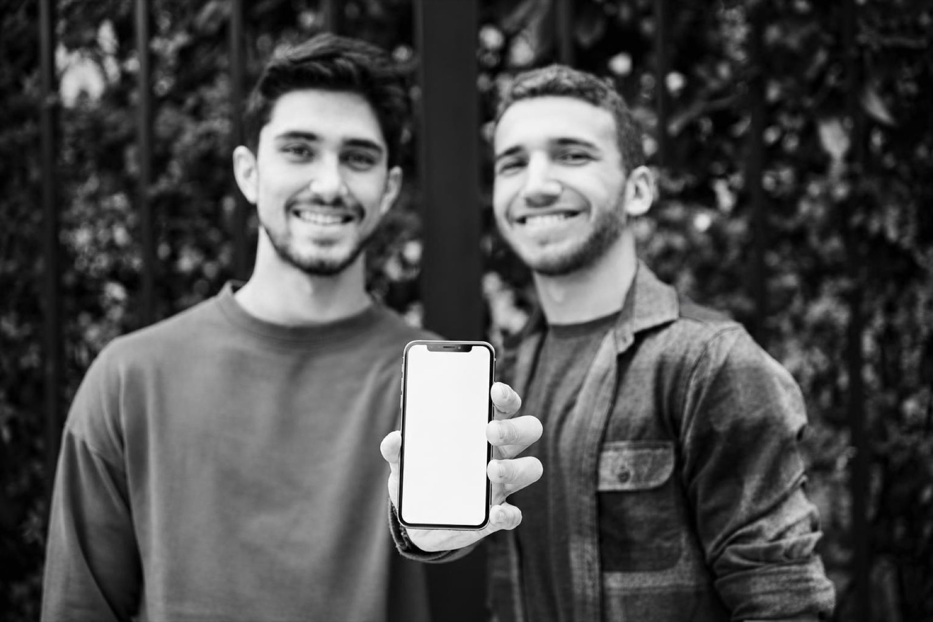 Two friends smiling while one shows the other a product on their phone