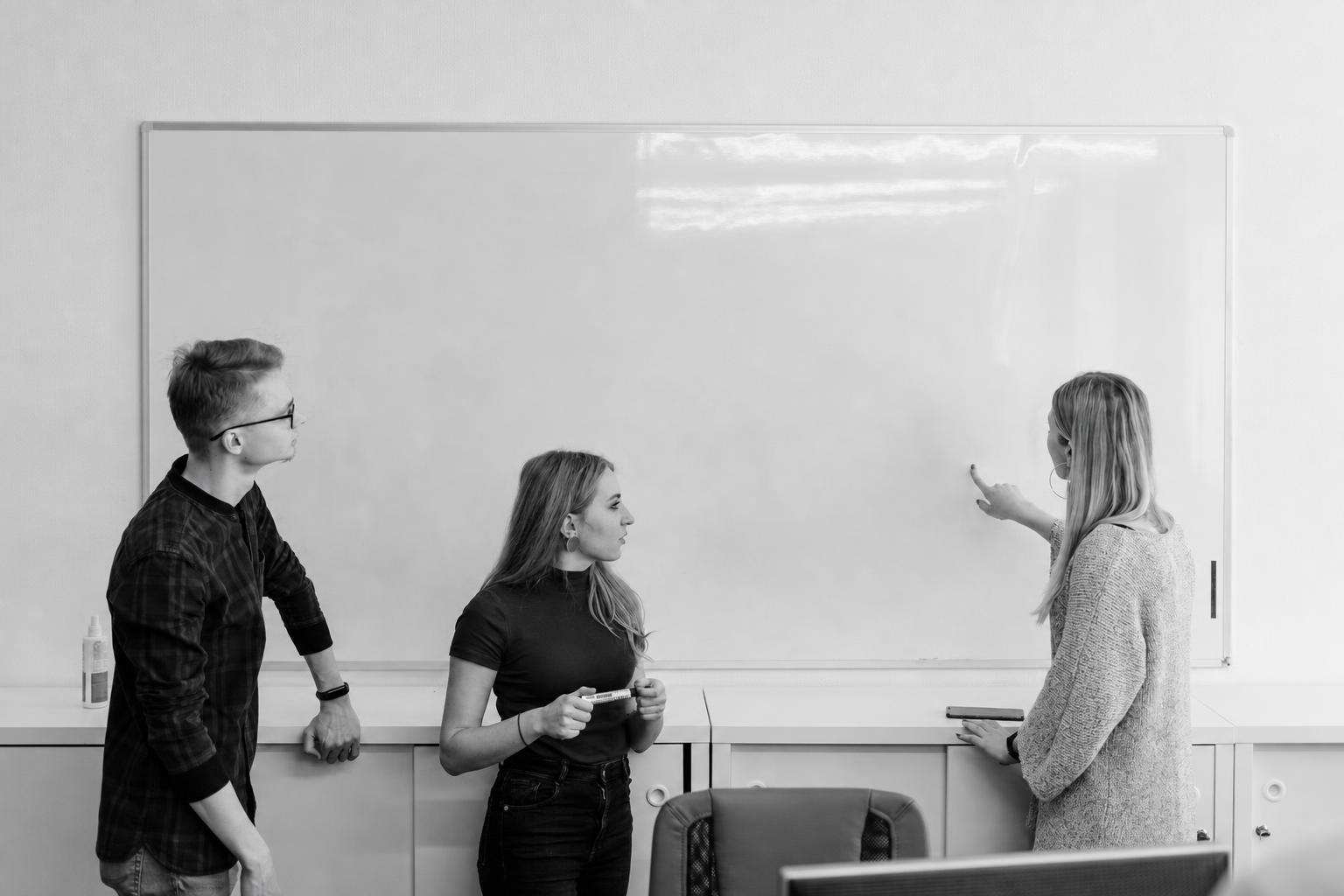 A founder and developer comparing a browser mockup against a native app mockup on a whiteboard