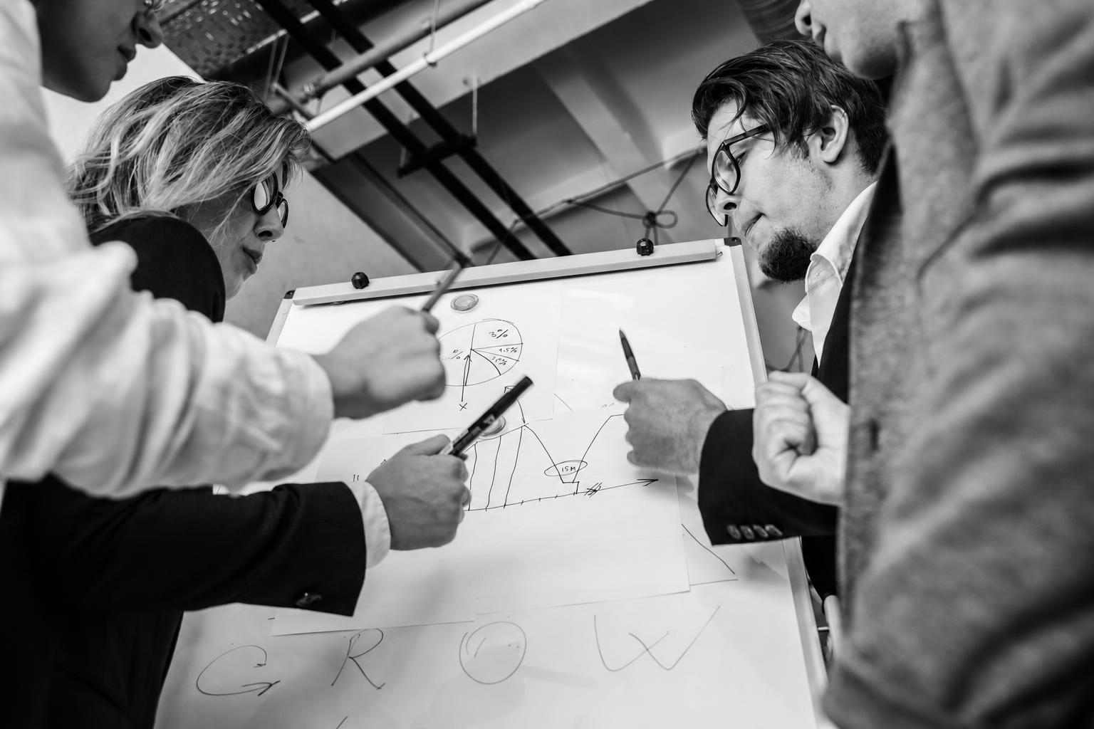 A designer and developer reviewing a tech stack diagram on a whiteboard